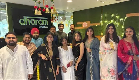 The team in the office beneath the Dharam Digital sign during a Diwali celebration